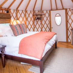 A queen size bed with white linens in a Pacific Yurt.
