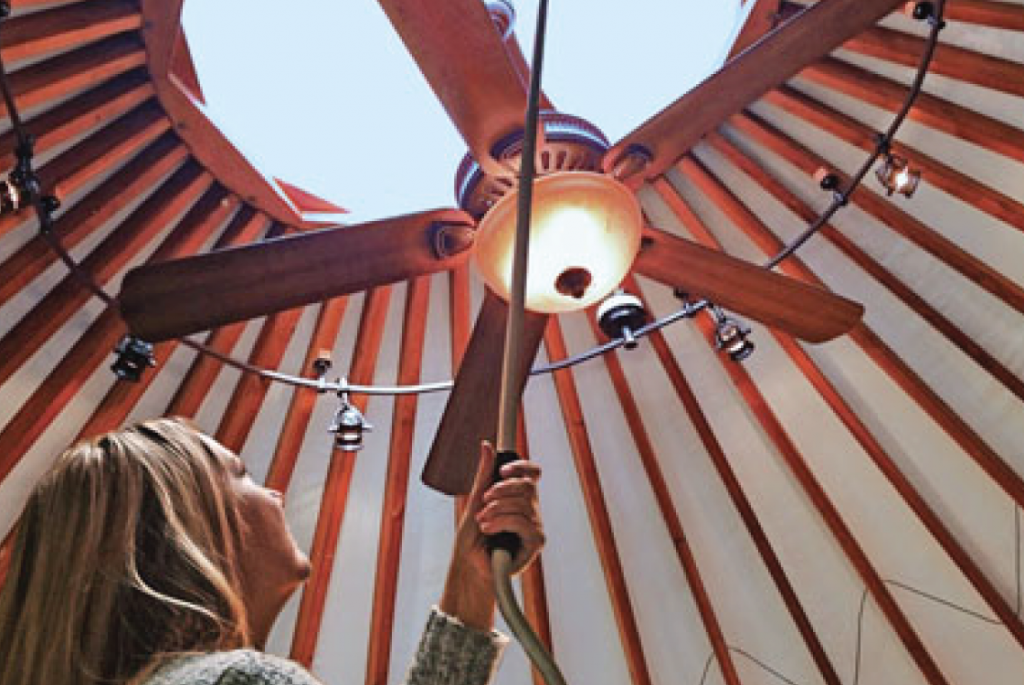 woman cleaning fan in ceiling of pacific yurt.