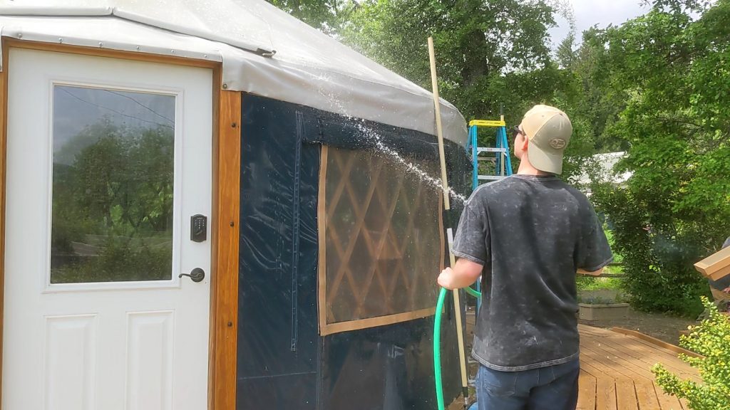 Man washing the outside cover of a Pacific Yurt.