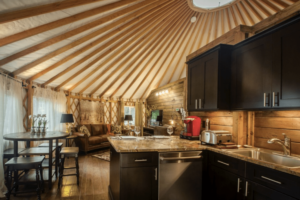 Small kitchen in a yurt with black wooden cabinets hanging on the wall above the sink.